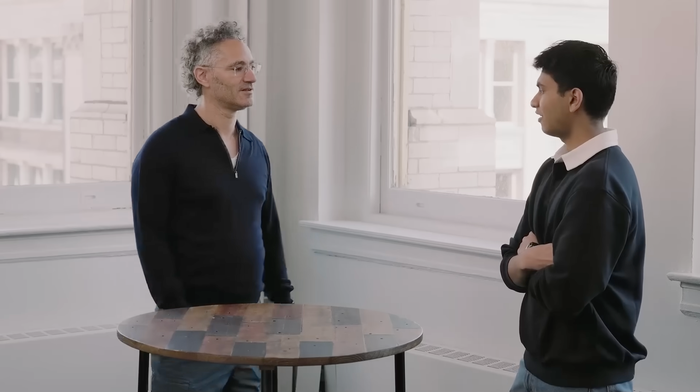 CEO Alex Karp speaking with a Palantir employee at a table
