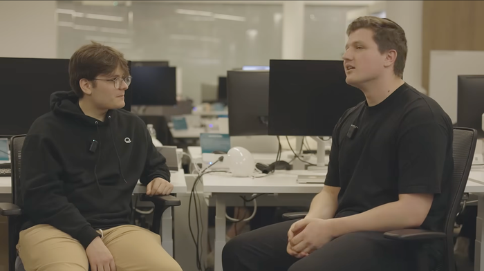 Two Palantir employees speaking at their desks.