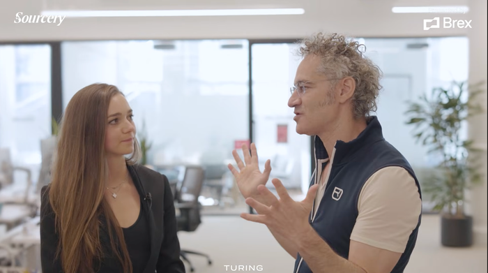 Alex Karp being interviewed while walking through the Palantir office
