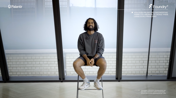 A Palantir hiring manager sits on a stool, speaking. 